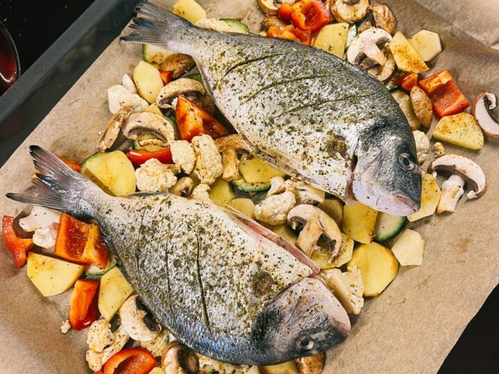 Pescado sobre papel de horno con vegetales listo para hornear