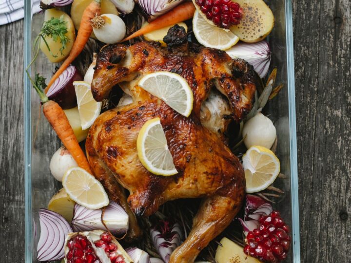 Pollo al horno con rodajas de limón y vegetales en una bandeja