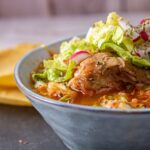 Pozole con lechuga y rábano en un plato hondo